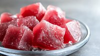 Fresh watermelon cubes covered in frost and ice crystals on glass plate, extreme close up macro shot showing juicy texture and frozen crystalline surface.
