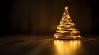 Glowing golden spiral Christmas tree on a dark wooden background with warm light reflections, festive holiday decoration concept.