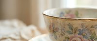 Elegant vintage teacup with delicate floral pattern and gold rim on soft fabric background, perfect for tea time, dining concepts and home decor projects.
