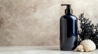 Navy blue cosmetic pump bottle with seashells and dried plants against neutral textured background, minimalist spa composition for beauty product presentation.