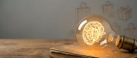 Vintage Edison bulb glowing on wooden surface with shopping bag sketches on wall background for retail and commerce concepts.