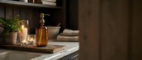 Cozy bathroom counter with amber glass bottles, candles, and towels creating warm spa atmosphere for relaxation and self-care routines.