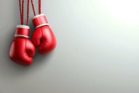 Red boxing gloves hanging on laces against neutral gray background with copy space, symbolizing competition, challenge and fighting spirit in sports.