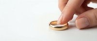 Gold wedding band being held by a hand against a white background, symbolizing marriage commitment and engagement jewelry for wedding planning and bridal design projects.