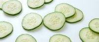 Fresh cucumber slices arranged on white background, healthy vegetable ingredient for salads, cooking and food preparation in kitchen.