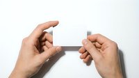Young adult male hands holding and breaking a gray rectangular object against white background, representing stress, frustration, or problem-solving concepts for business and personal development.