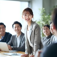 Confident Asian businesswoman leading team meeting in modern office with colleagues smiling during corporate presentation and strategy discussion.