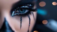 Close-up of woman's eye with dramatic black glitter makeup and long eyelashes. Dark artistic beauty look with sparkling cosmetics and bokeh lights.