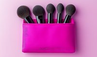 Professional makeup brushes set in bright pink silicone holder against pink background. Clean minimal cosmetic flatlay composition for beauty and fashion content.