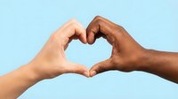 Two hands of different skin tones forming a heart shape together on a light blue background, symbolizing unity, love, and diversity.