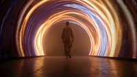 Businessman walking through futuristic tunnel with glowing circular light rings creating dramatic perspective and modern architectural atmosphere.