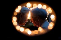 Romantic silhouette of senior couple in love framed by glowing bokeh lights creating heart shape, intimate moment captured in warm evening atmosphere.