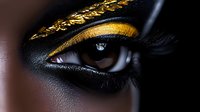 Close up of dark-skinned female eye with luxurious gold and black artistic makeup, dramatic fashion beauty photography with metallic eyeshadow and creative cosmetics.