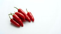 Fresh red chili peppers isolated on white background, ready for culinary, food packaging, and recipe design projects.