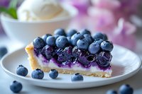 Fresh blueberry pie slice with cream cheese filling on white plate, garnished with whole berries, selective focus on purple fruit against soft background.