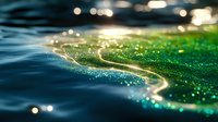 Glowing bioluminescent waves create magical light pattern on dark ocean surface with sparkling bokeh effect and emerald green illumination in night water.