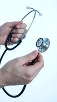 Doctor hands holding stethoscope on white background, medical professional equipment for healthcare examination and diagnosis in clinical setting.