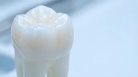 White ceramic dental crown model on soft blue background for dentistry education and oral health care presentations.