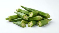 Fresh green okra pods with sliced cross-sections showing star-shaped interior pattern, isolated on white background for culinary and cooking designs.