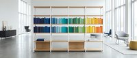 Modern office interior with colorful organized bookshelf displaying rainbow spectrum of books in contemporary workspace with natural light and minimalist design.