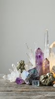 Collection of healing crystals and gemstones including amethyst quartz fluorite and pyrite arranged on rustic wooden surface for meditation wellness.