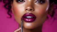 Young African American woman with burgundy lipstick and glamorous makeup against pink background, demonstrating professional cosmetics application and beauty trends.