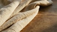 Handmade fresh pasta noodles on rustic wooden surface, artisanal Italian cuisine preparation for cooking and culinary arts projects.