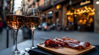 Two glasses of rosé wine with charcuterie board on urban restaurant terrace at golden hour, perfect for dining and hospitality marketing materials.