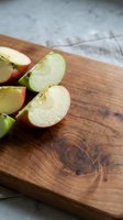 Fresh apple slices on rustic wooden cutting board ready for healthy snacking or cooking preparation in modern kitchen setting.