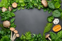 Fresh green herbs, mushrooms and citrus create natural frame border on dark background with copy space for menu or recipe design layout.