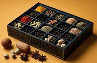 Wooden box with assorted colorful spices and herbs in compartments, star anise and cardamom pods on golden background for cooking and culinary use.