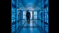 IT professional walking through modern data center corridor with glowing blue server racks for technology and cloud computing concepts.