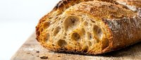 Freshly baked artisan bread loaf with crispy crust and airy crumb structure, sliced to reveal soft interior. Perfect for bakery, food, and culinary design projects.