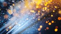 Magical glowing particles with golden bokeh lights on dark blue background create dreamy atmosphere. Abstract defocused sparkles for festive designs.