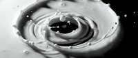 Liquid splash forming spiral vortex with droplets suspended in motion against dark background, suitable for abstract and dynamic design projects.