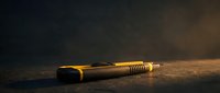 Golden tactical flashlight on dark textured surface with dramatic lighting and moody atmosphere for security and outdoor adventure concepts.