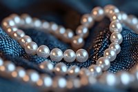 Elegant pearl necklace on dark blue textured fabric creates luxurious contrast with soft lighting and shallow depth of field for jewelry and fashion photography.