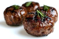 Juicy grilled meatballs garnished with fresh rosemary sprigs on white background, close-up view showing caramelized surface and herbs for gourmet appetizer presentation.