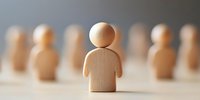 Wooden figure standing out from crowd, leadership concept shown through minimal design composition on light background. Business recruitment and talent selection.