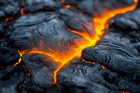 Glowing orange lava flow creates dramatic patterns through dark volcanic rock, showcasing nature's raw power in close-up detail. Perfect for geology publications.