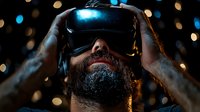 Bearded man wearing virtual reality headset against blurred bokeh lights background, dramatic lighting highlights technology immersion experience.