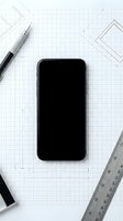Smartphone with blank screen surrounded by technical drawing tools and grid paper, ideal for app development, UI design, and technology mockups.
