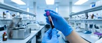 Scientist in blue gloves holding test tube with red liquid sample in modern laboratory for medical research and analysis.