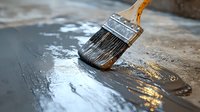 Paint brush with natural bristles applying clear varnish or sealant on wooden surface, creating glossy wet reflection with dramatic lighting effect.