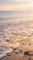 Soft ocean waves gently washing over pebbles on beach shore during golden hour sunset creating peaceful coastal atmosphere for relaxation and meditation backgrounds.