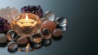 Healing crystals and gemstones arranged around glowing candle for meditation, spiritual wellness, chakra balancing and holistic therapy practices.