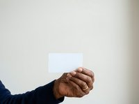 Close-up of a hand holding a blank white card against a neutral background, suitable for business, marketing, and promotional designs.