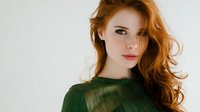 Young redhead woman with wavy hair wearing green sweater against neutral background for fashion and lifestyle projects.