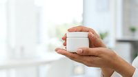 Close-up of male hands holding small white box in bright office environment, suitable for product packaging, gift presentation, and business concepts.