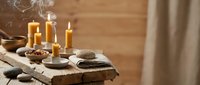 Spa wellness table setting with lit candles, stones, and folded towels on wooden surface for relaxation and meditation themes.